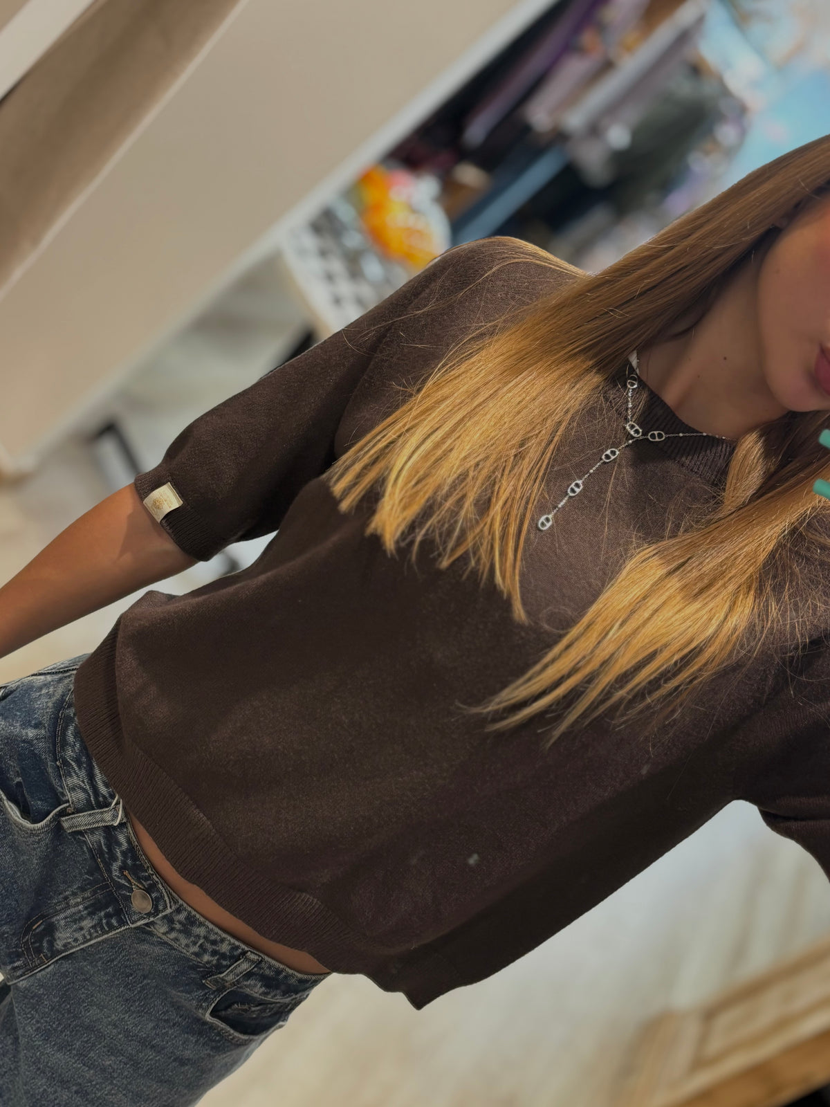 Détail du pull marron à manches courtes porté avec un jean
