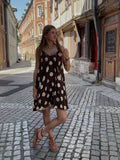 Robe courte chocolat à grands pois crème portée dans une ruelle pavée