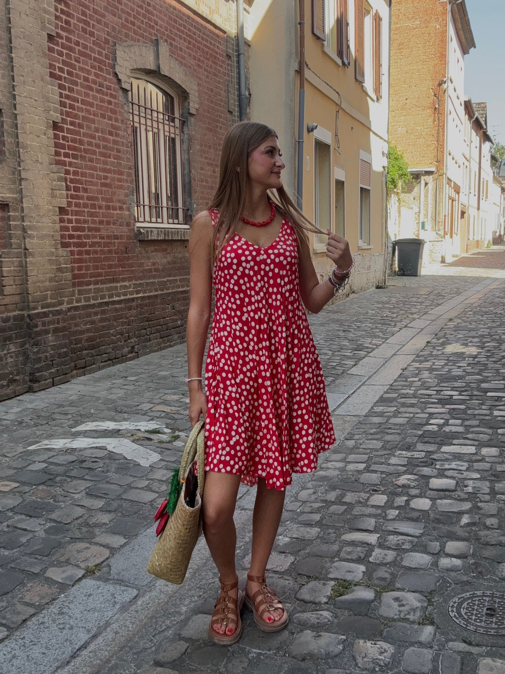 Robe rouge à pois fleuris portée dans une ruelle pavée