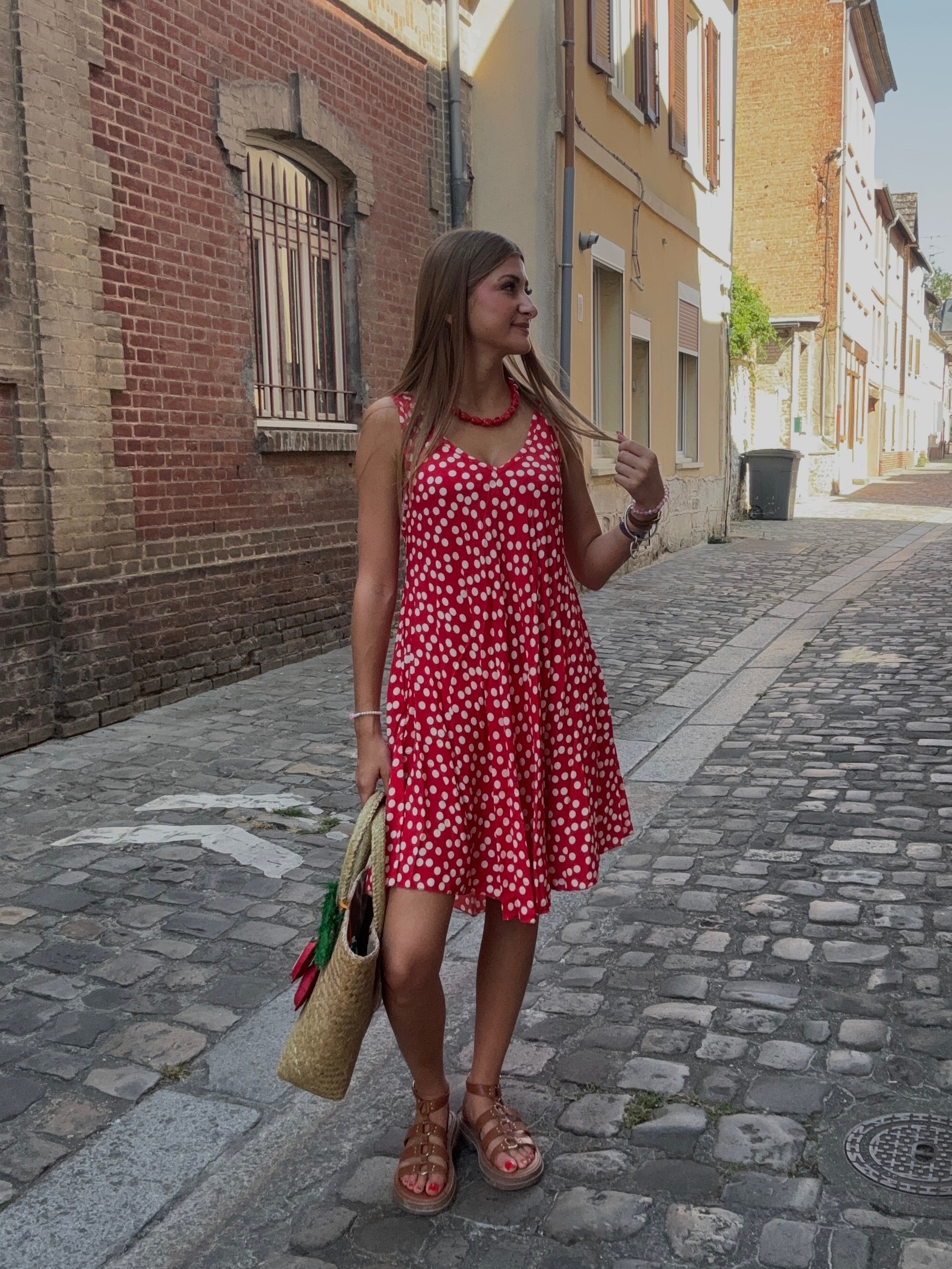 Robe rouge à pois fleuris portée dans une ruelle pavée