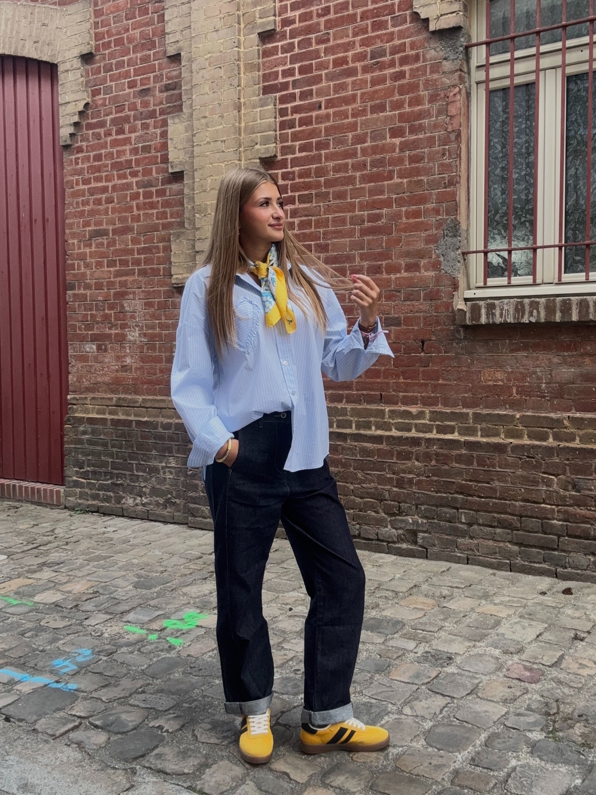 Chemise rayée bleue oversize portée avec un jean brut et des sneakers jaunes