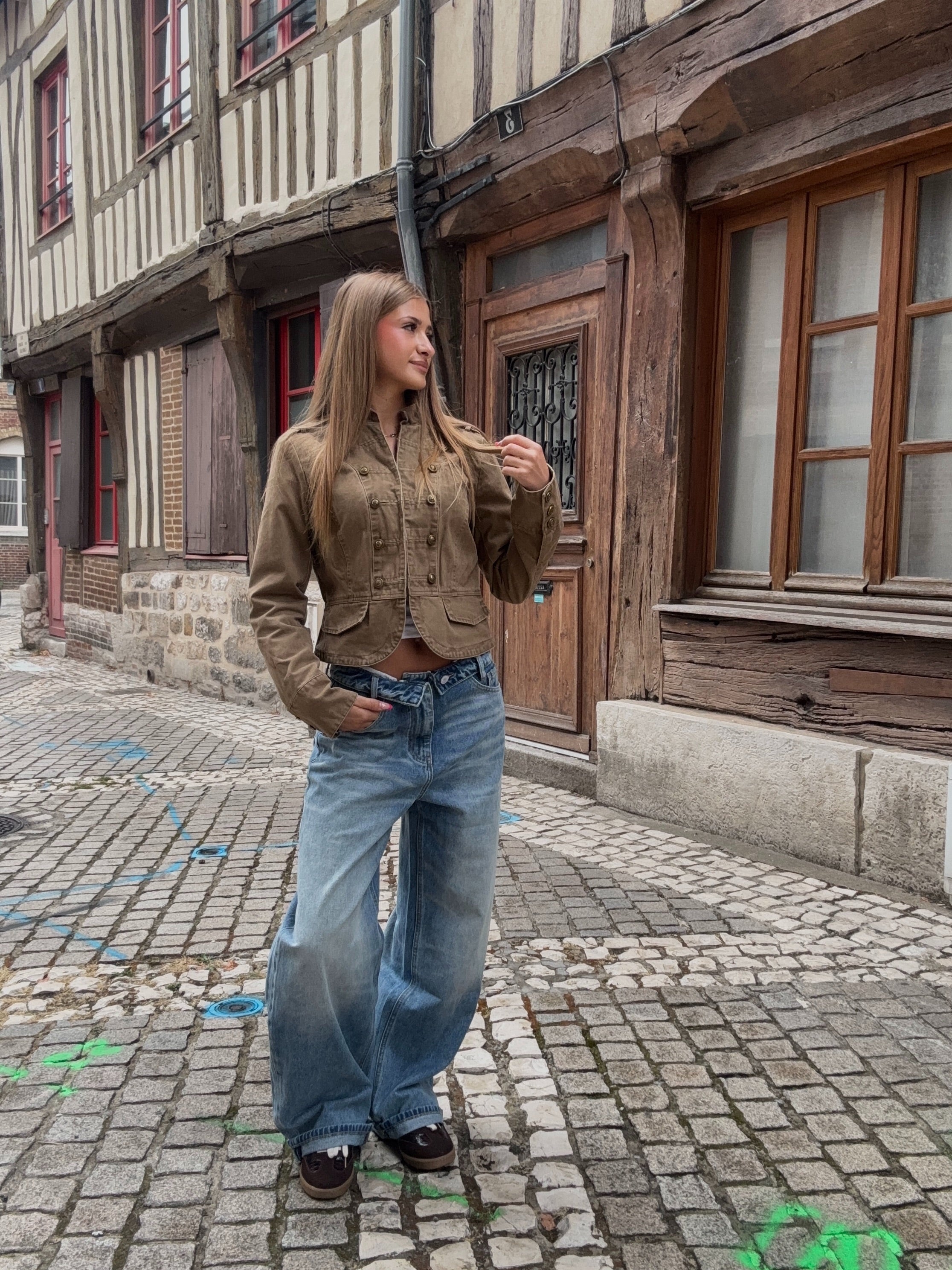 Veste crop militaire camel à boutons dorés portée avec jean wide leg bleu, vue de face
