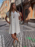 Robe chemise blanche boutonnée portée avec des mules beige
