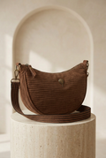 Sac demi-lune choco à texture côtelée horizontale avec bandoulière rayée et emblème montgolfière